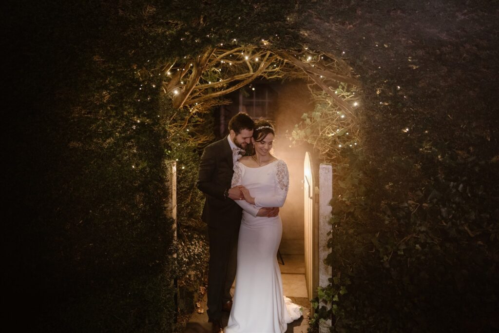Bride and groom under twinkle-lit archway