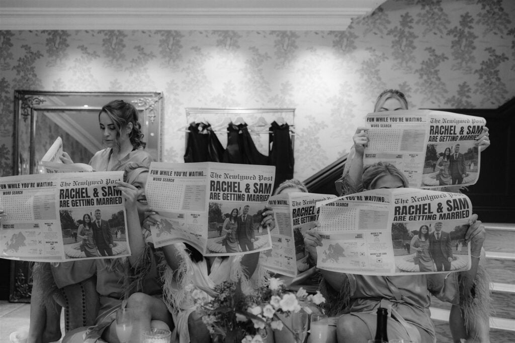 Bridesmaids reading newspapers about Rachel and Sam's wedding.
