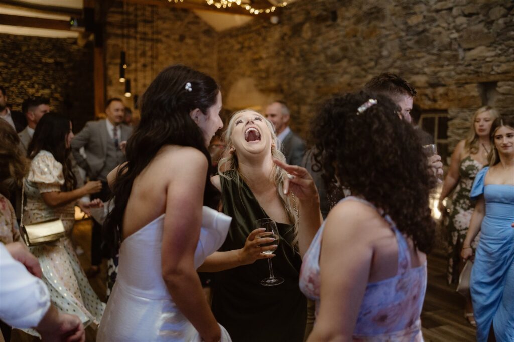 Guests laughing and dancing at wedding reception.