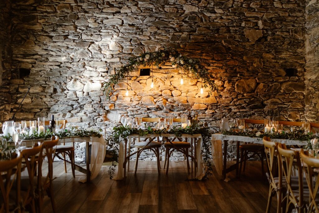 Rustic wedding dining area with stone walls and lights.