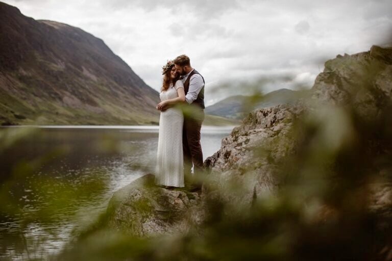 Groom embracing his wife after their elopement ceremony by a Lake