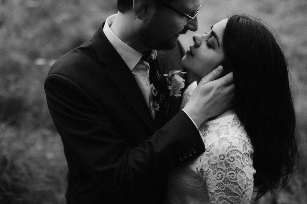 Groom holding head of his wife as she tips it back to kiss him
