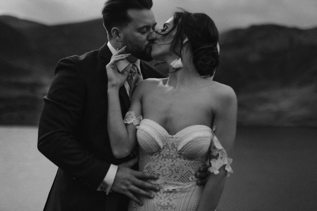 Bride kissing husband over her shoulder during their elopement