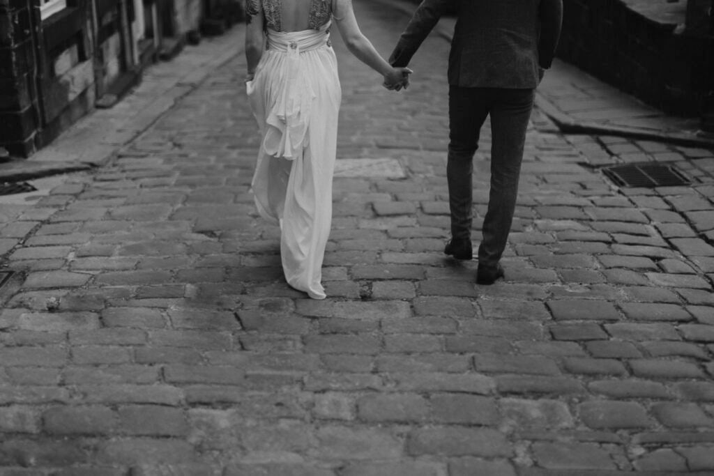 Couple walking hand-in-hand down cobbled street