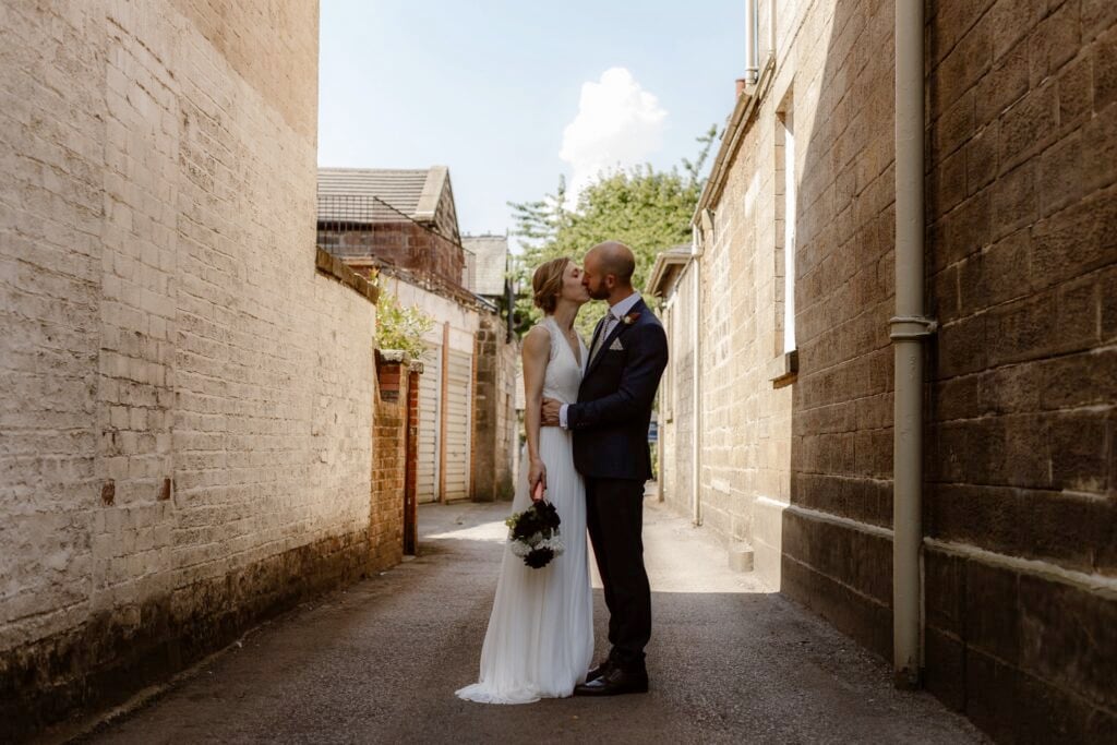 Couple kissing in an urban alleyway during their micro wedding