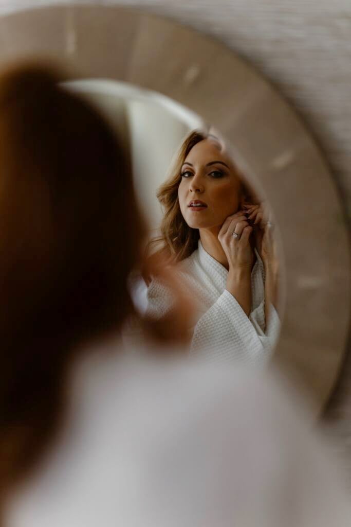 Bride getting ready putting earrings in on the morning of her elopement