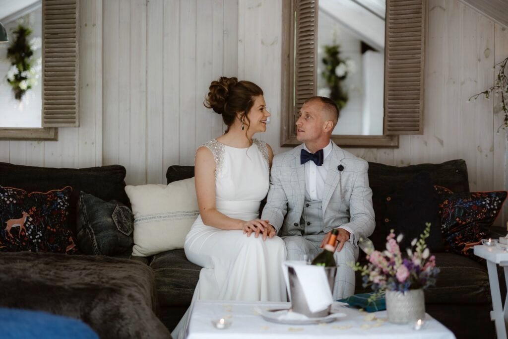 Couple sat on couch holding hands before their elopement ceremony
