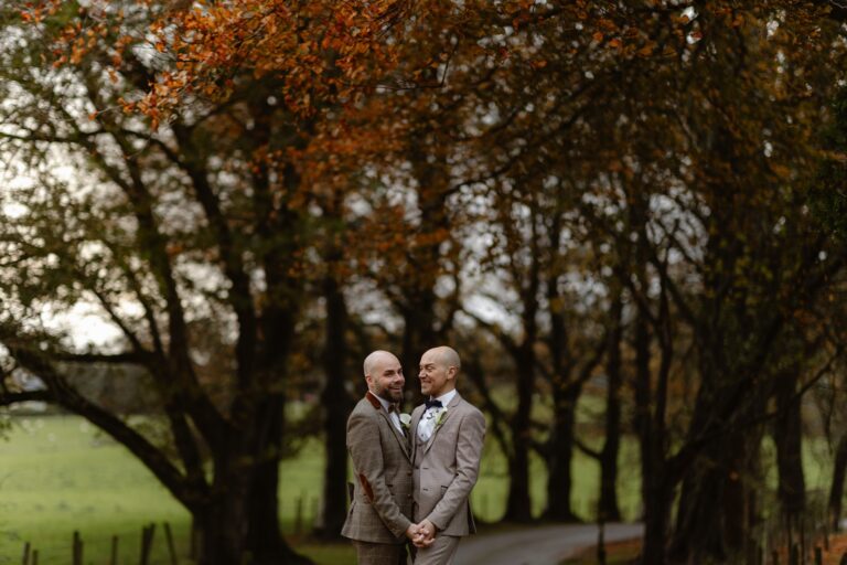 Male LGBT Couple holding hands on driveway of their wedding venue
