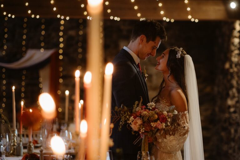 Bride & groom embracing with candles in foreground