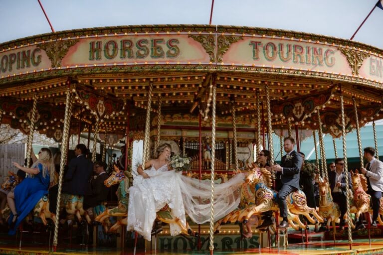 Bride & groom riding on a carousel as Bride's dress flows behind her