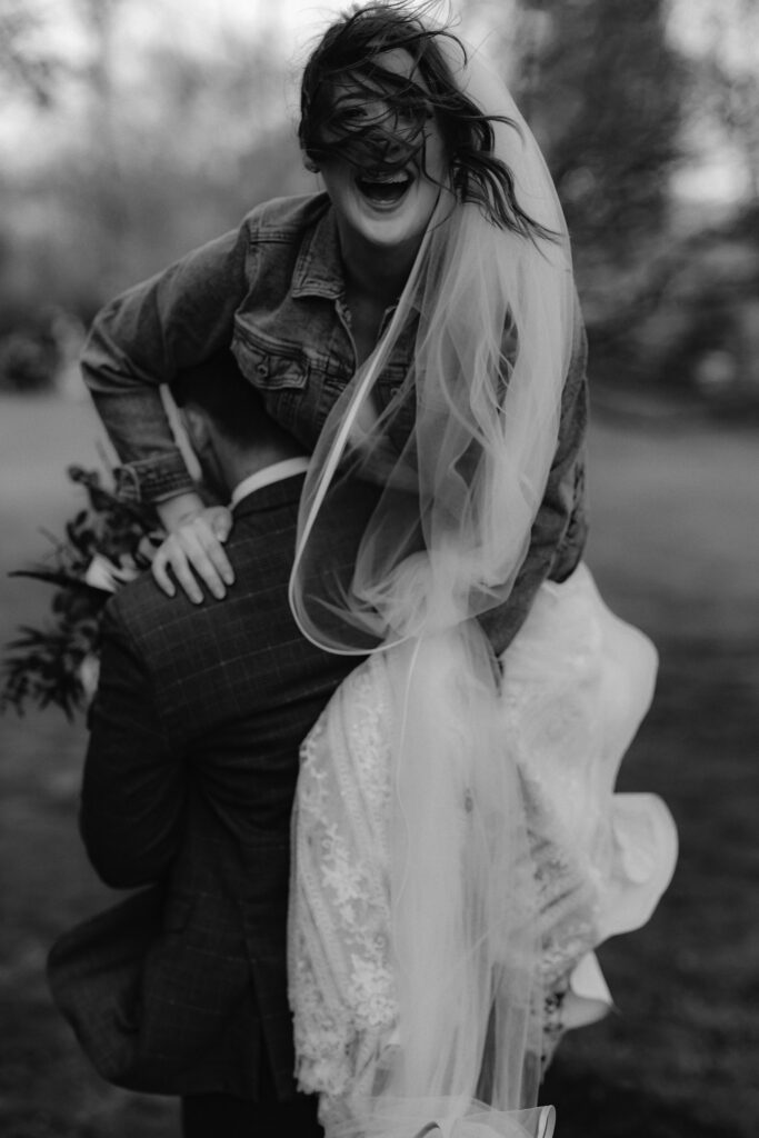 Image of Bride laughing as the husband lifts her over his shoulder