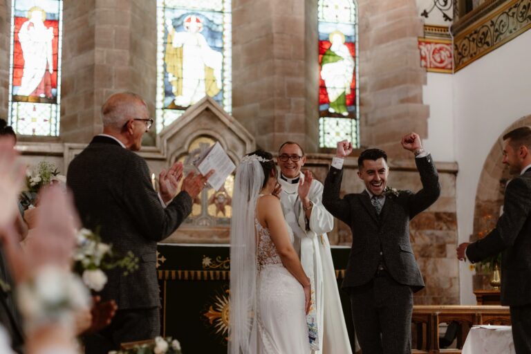 Groom celebrating marriage by punching the air after his wedding ceremony in church