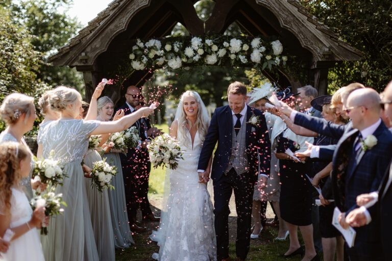 Confetti shot as couple leave church and guests shower them with confetti