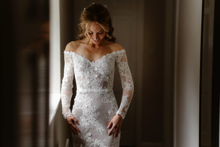 Bride smiling as she looks down at her wedding dress