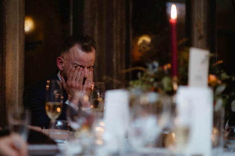 Groom rubbing eyes crying during wedding speeches