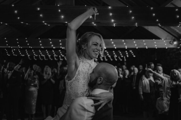 Bride fist pumping air as husband picks her up