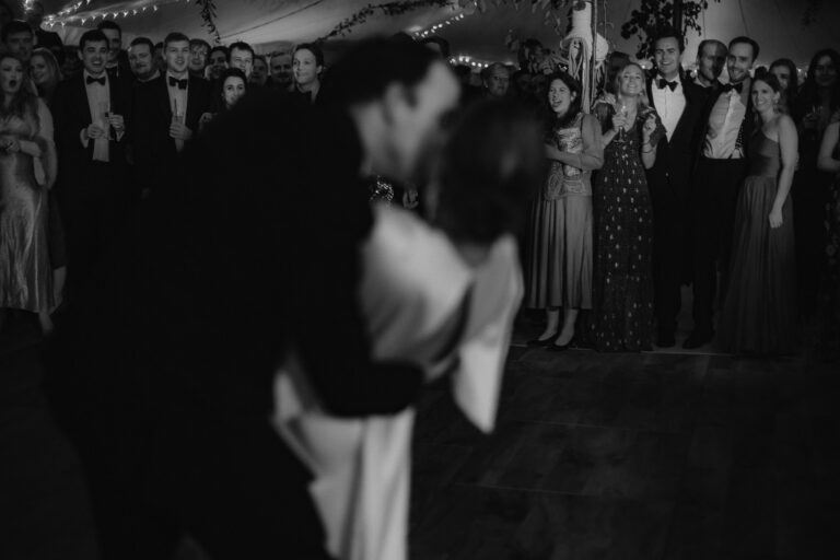 Couple kissing during first dance as guests cheer