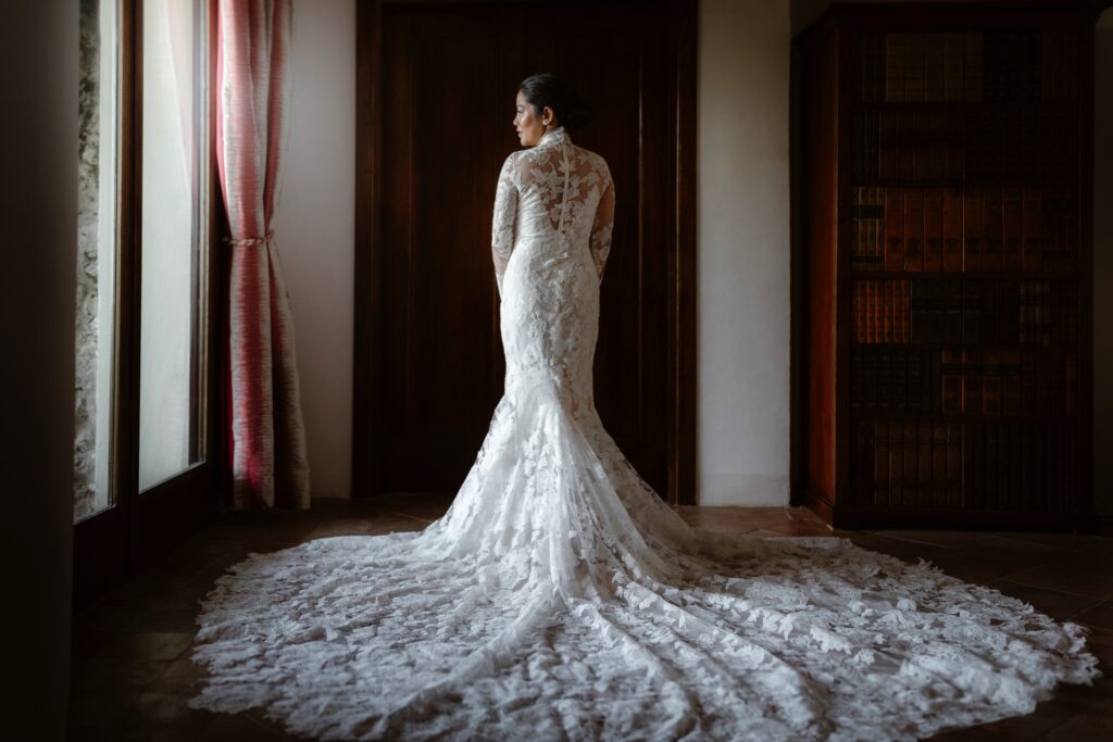 Bride looking out of the window with her wedding dress fanned out behind her