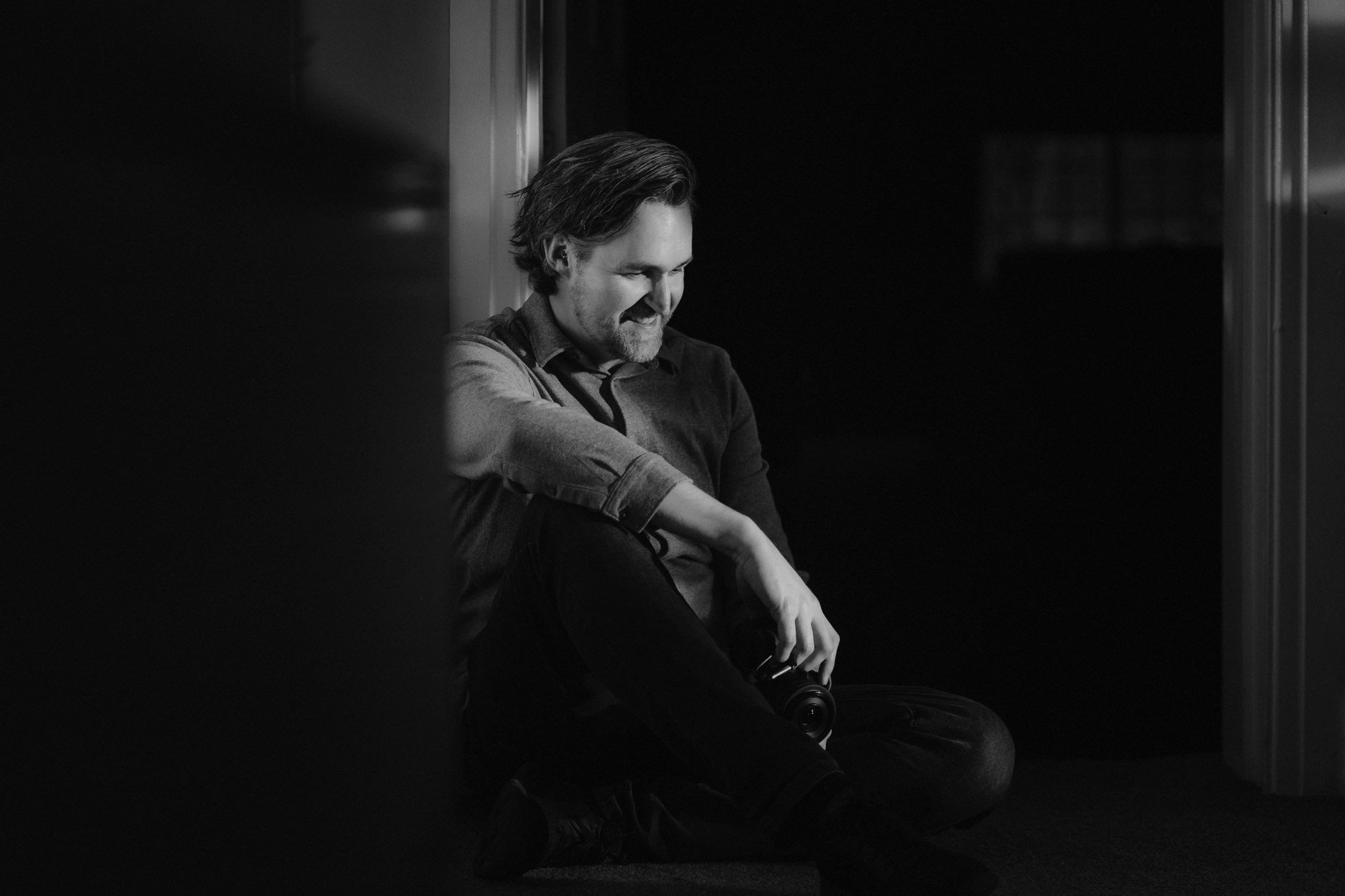 Portrait of Lake District Wedding Photographer & Videographer Jono Symonds sat on the floor with camera in hand