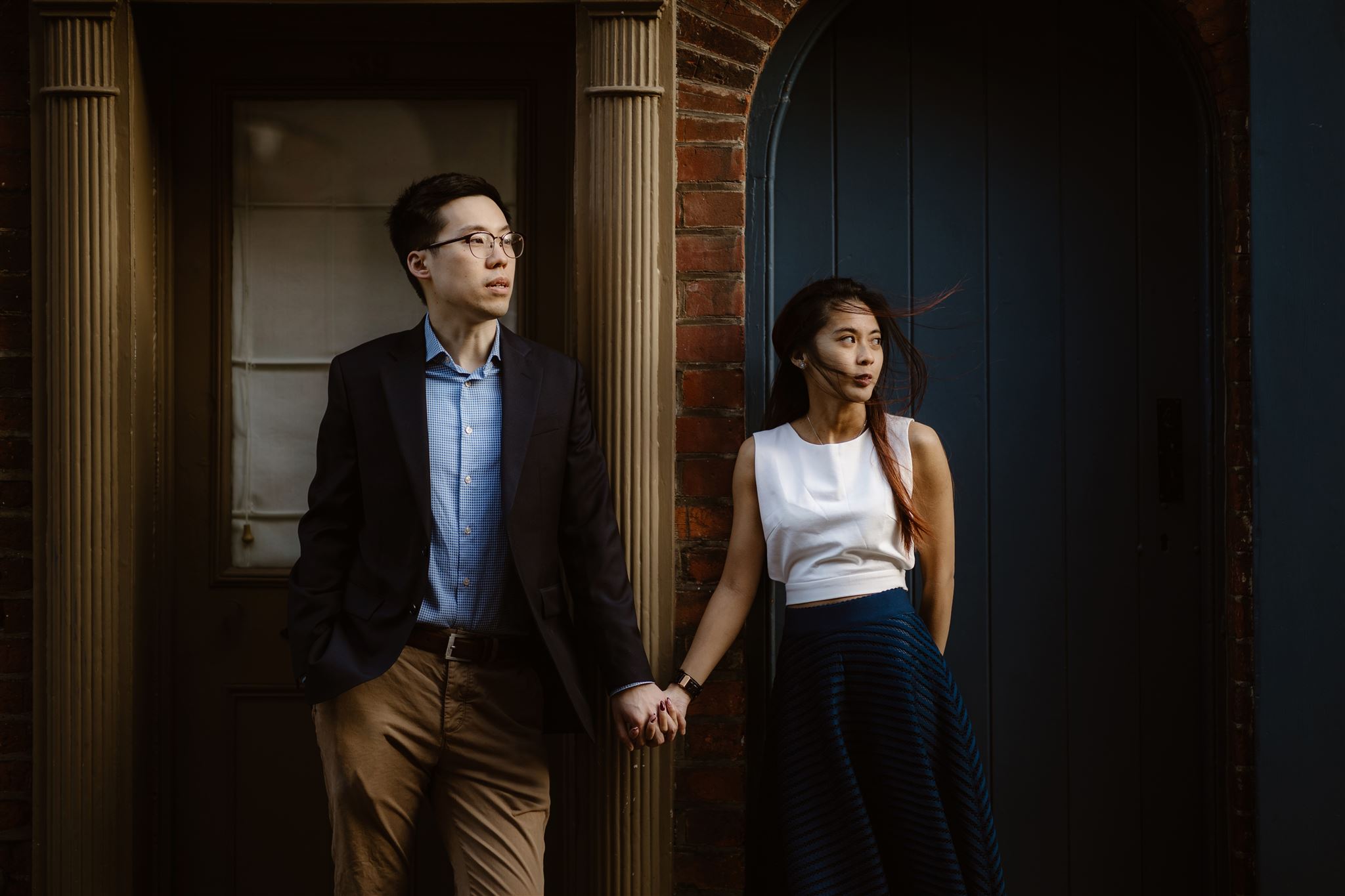 Couple stood between two different house doorways holding hands during their engagement shoot in Norwich