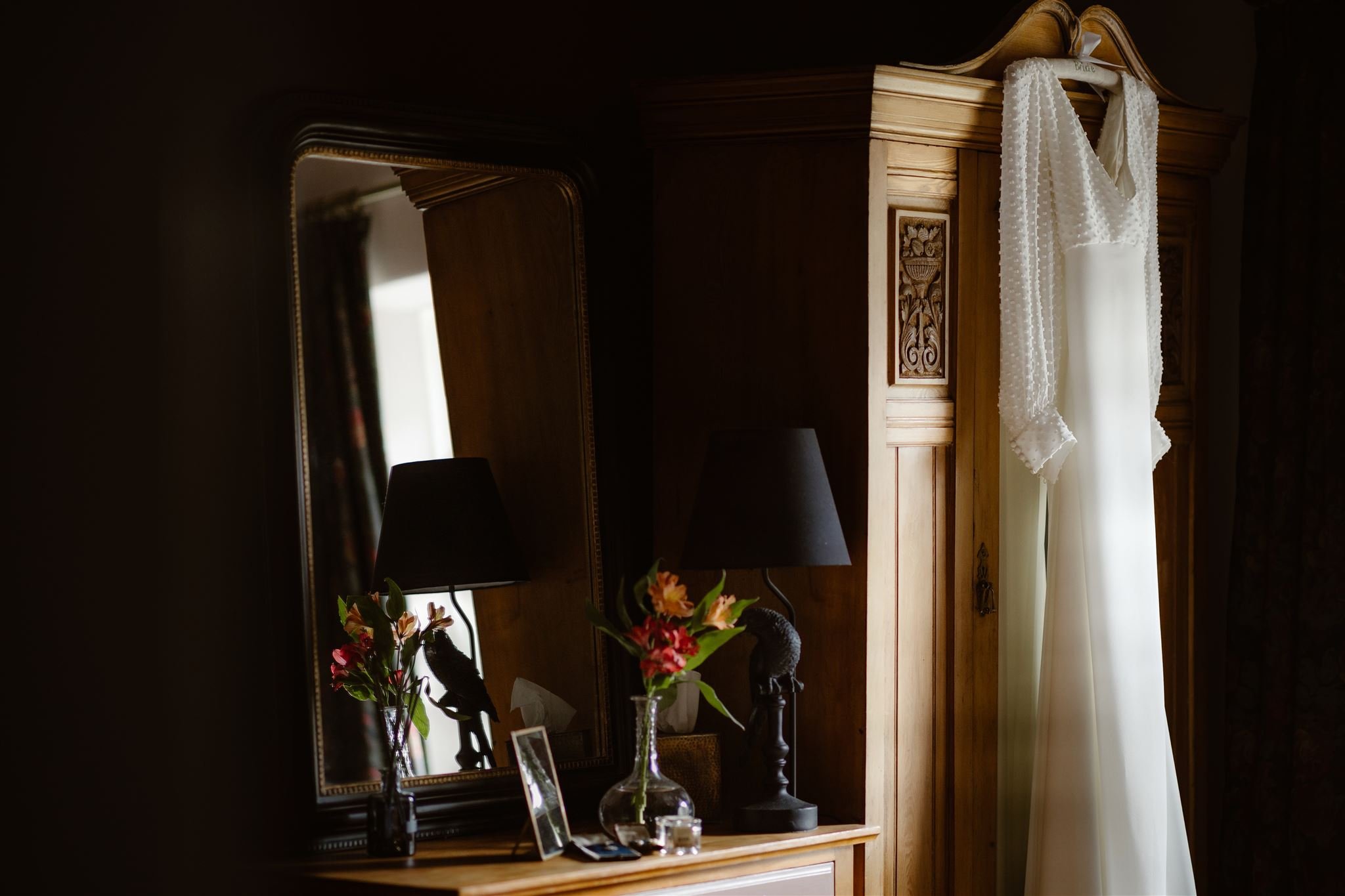 White dress hanging on carved wooden wardrobe.