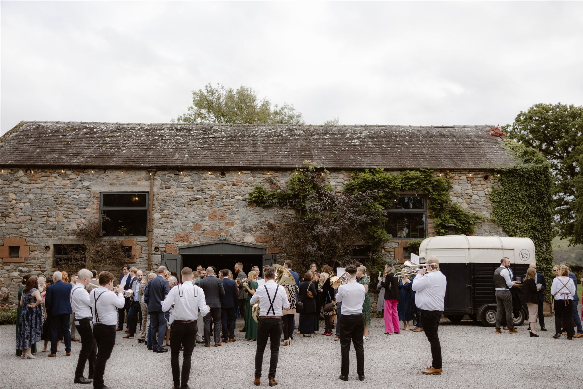 People socialising outside rustic stone barn.