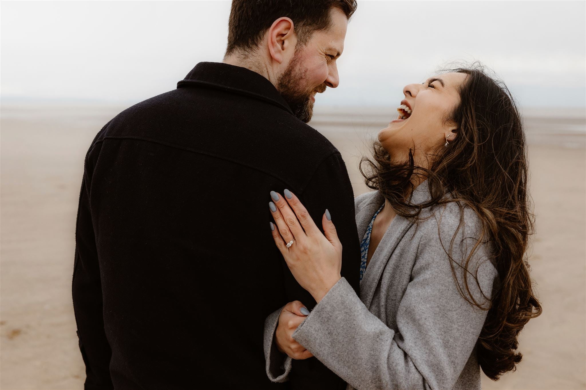 Couple laughing during their engagement shoot at Formby Beach